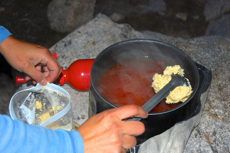 Putting corn dumpling batter on top of salsa soup