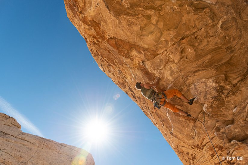 adventure sports photography image of rock climber ascending a steep roof