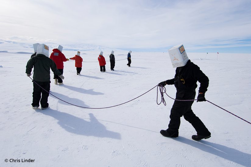 A group of researchers hold a rope while practicing a rescue operation
