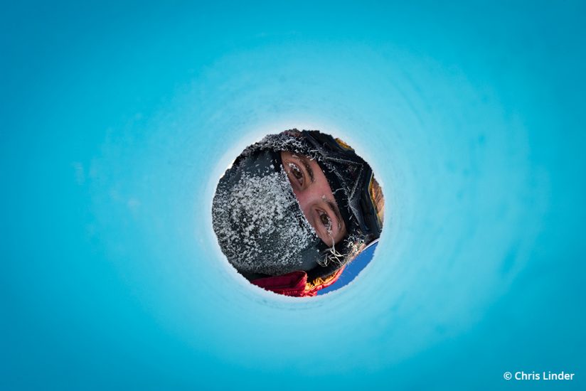 Photo of a researcher peering through a hole cored through sea ice
