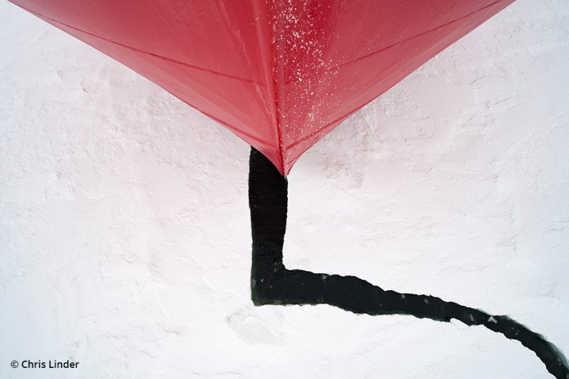Graphic photograph of the tip of a boat breaking through ice