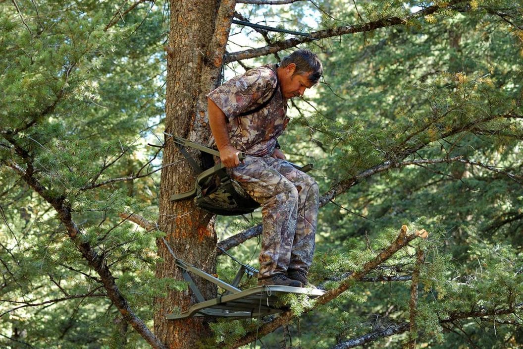 Male hunter sets up a hang on treestand