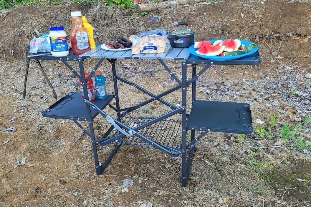 The GCI Outdoors Slim-Fold Cook Station set up in the woods.