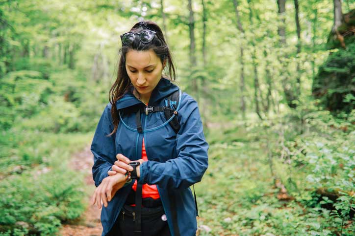 Female hiker stands in the woods and checks her watch