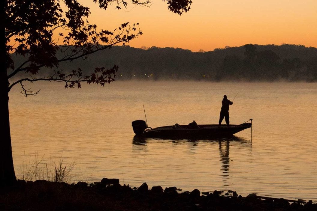 Bass angler fishes on a lake at sunrise