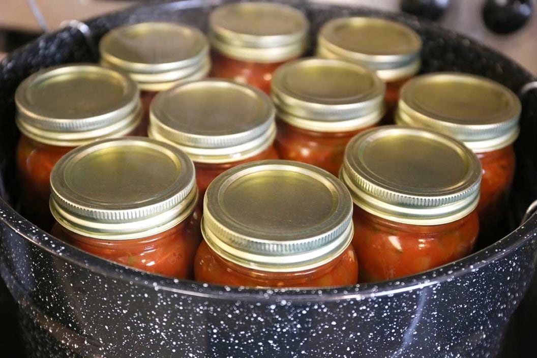 Cans of salsa waiting to be sealed in a pot of water