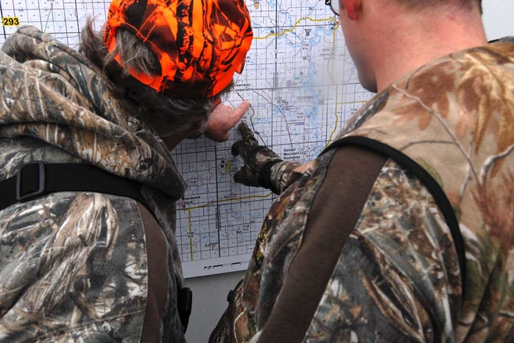 Two deer hunters look at a map