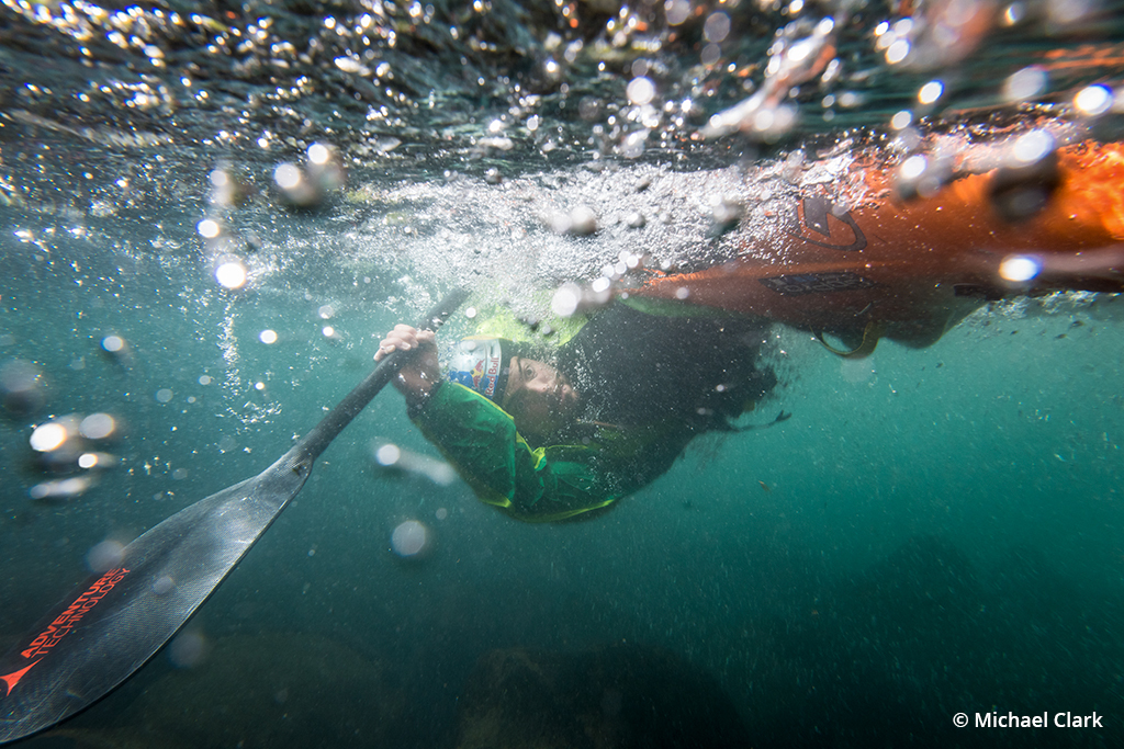 Photo of Rafa Ortiz rolling up while whitewater kayaking