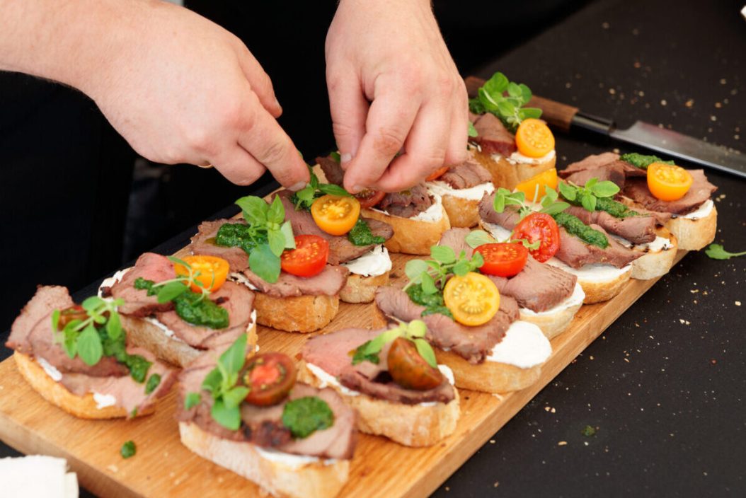 Chef is making bruschettas with meat and pesto sauce